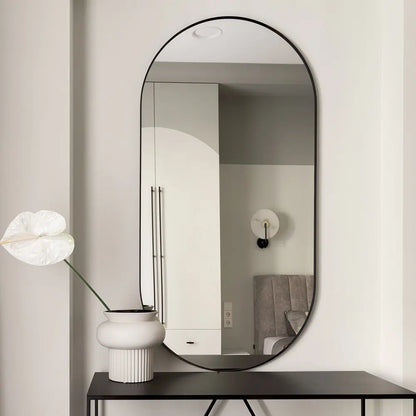 Oval aluminium-framed bathroom mirror reflecting vanity and lighting fixtures