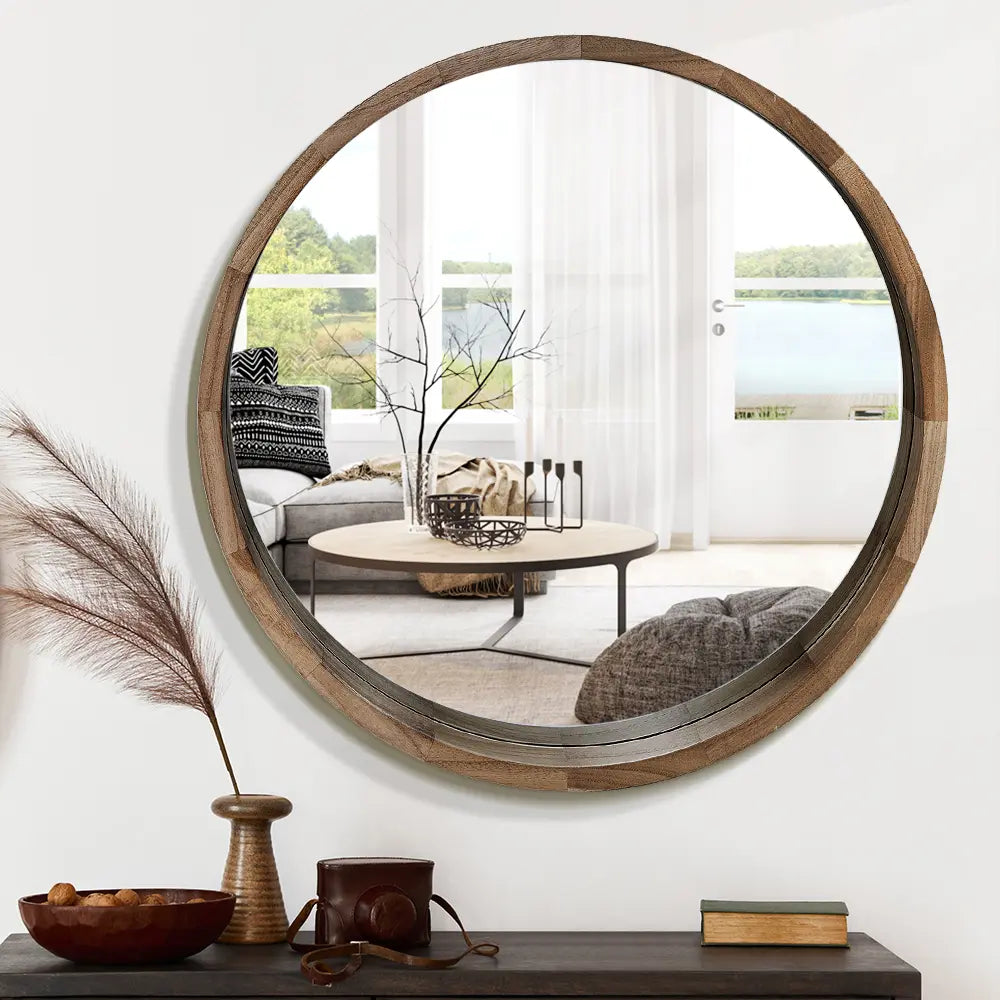 Libra Round Mirror hanging on wall with natural wood finish